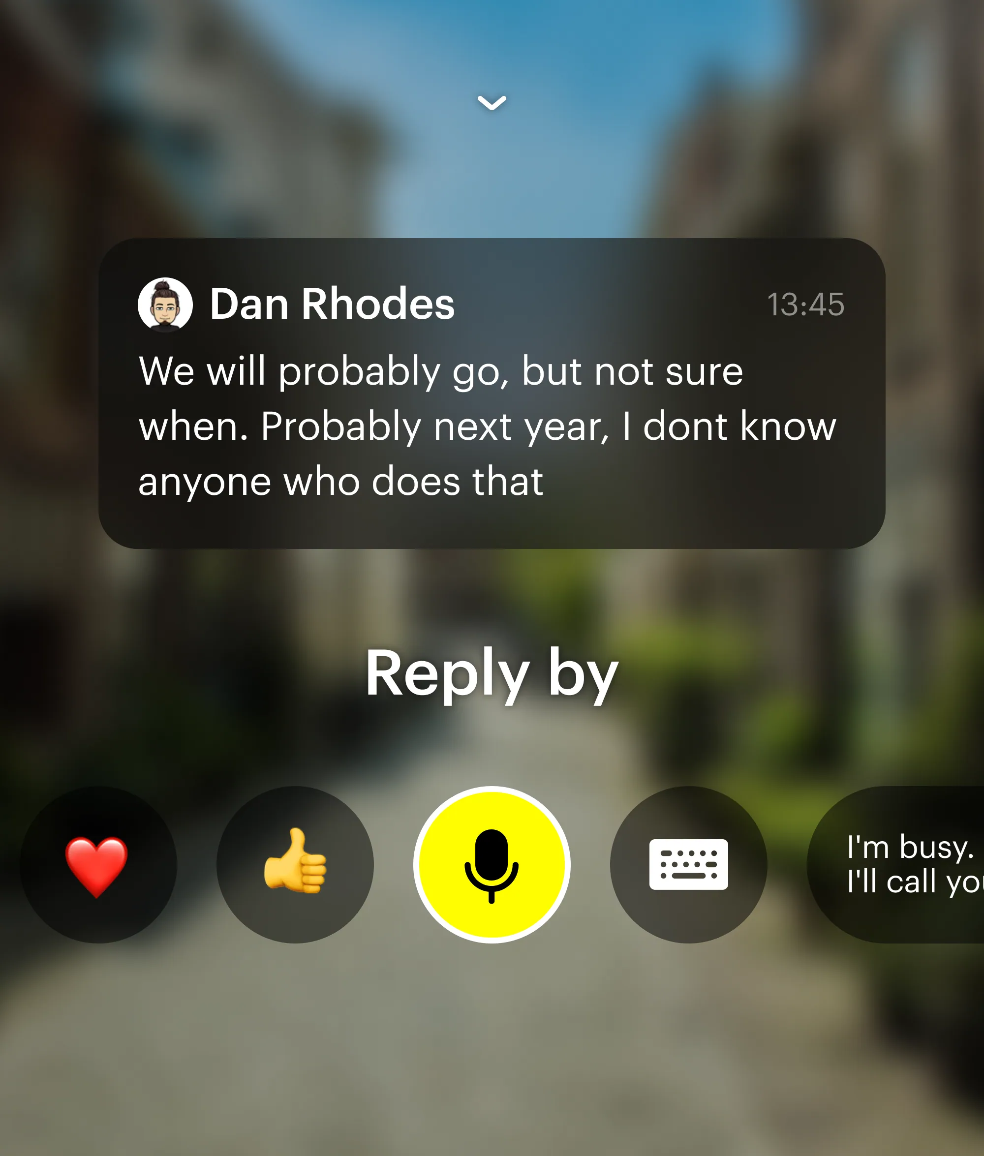 A message from a friend floating over a blurred street, with reply options under it